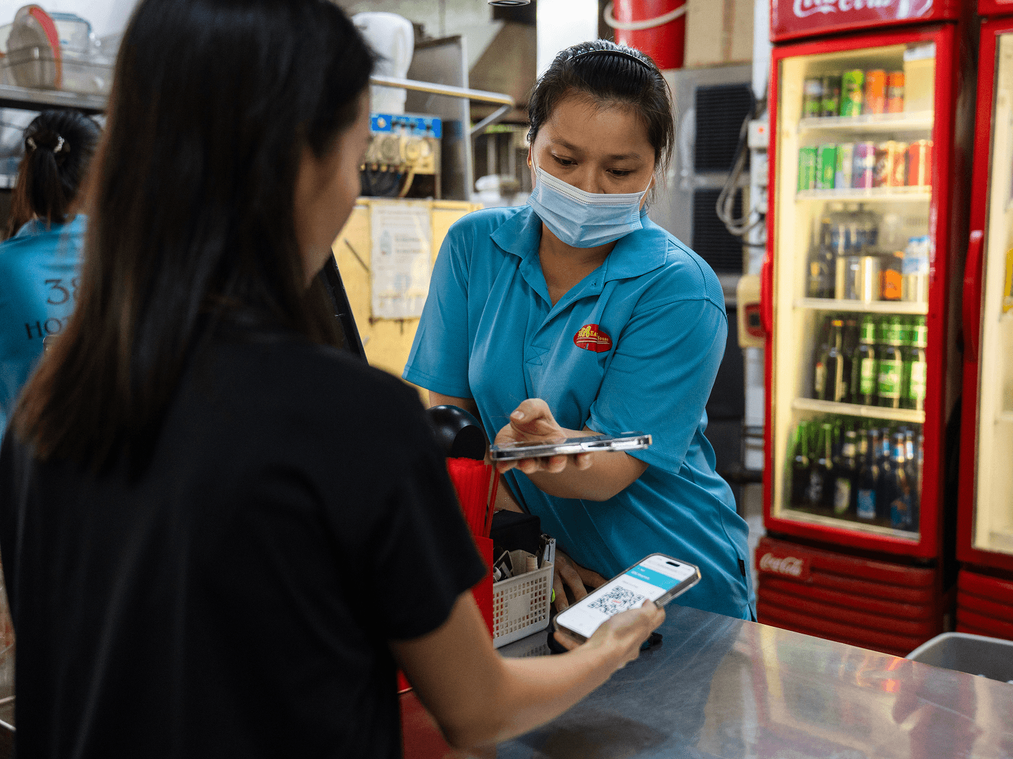 A hawker scanning a customer's digital voucher